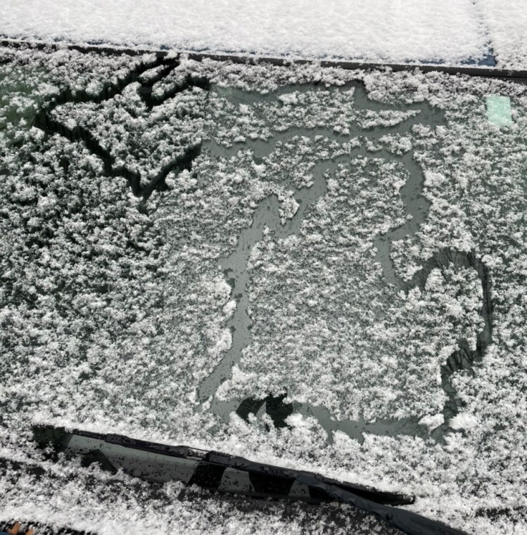 Shows an image of the outline of the state of Michigan traced into snow that has fallen onto the windshield of a car
